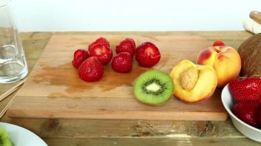Bir kesme tahtası üzerinde meyve kokteyli için tedarik muz, çilek, şeftali, kivi, Hindistan cevizi.