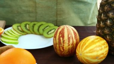 Bir kesme tahtası üzerinde olan bir tabakta portakal parçaları bir kadın koyar.