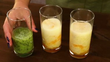 Kitle ezilmiş kivi smoothies iki bardak içine bir kadın eli tarafından dışarı dökülür