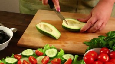 Kadın avokado küçük parçalar halinde bıçakla keser. Yakın çekim.