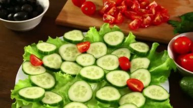 Bir kadın bir plaka ile yeşil salatalık domates bir dilim koyar. Yakın çekim.