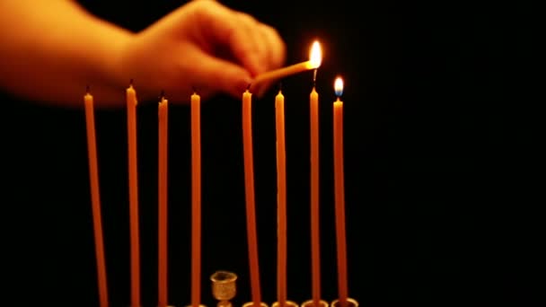 一个女人手里拿着蜡烛 在光明节烛台上点燃蜡烛 相机从右向左移动 — 图库视频影像
