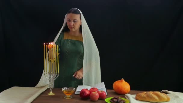 Una donna ebrea accende candele in un candelabro festivo in onore di Rosh Hashanah e legge una benedizione . — Video Stock