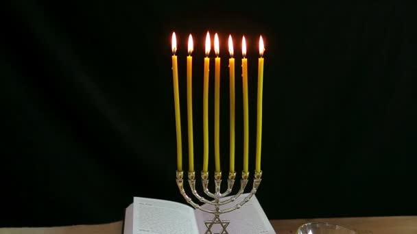 On the table are traditional treats on Rosh Hashanah: pomegranate, apple, honey and hala. Next a festive prayer book and a menorah with candles. — Stock Video