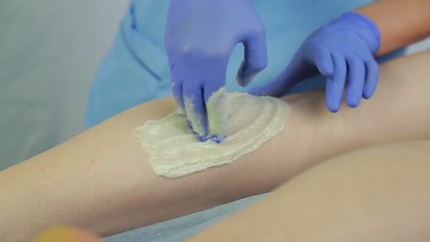 Una joven doctora esteticista prepara la piel de las piernas de las niñas para el procedimiento de encorvamiento . — Vídeos de Stock