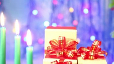 Yanan Noel mumlar ve hediyeler kırmızı yay ile bulanık ve odak bir şekilde dekore edilmiş dala döner.