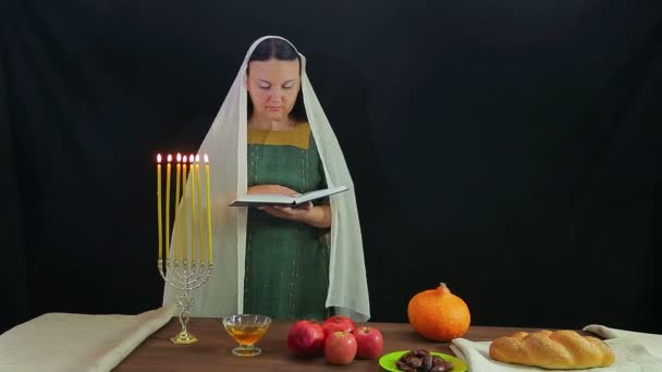 Una mujer de los Judios lee una oración en honor de Rosh Hashaná. Cerca de quemar velas . — Vídeos de Stock