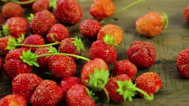 Erdbeeren liegen auf einem Holztisch. Nahaufnahme. die Kamera bewegt sich von rechts nach links zum Dolly — Stockvideo