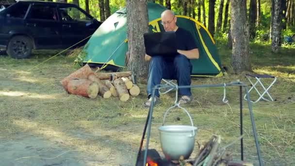 Um homem perto da tenda está a trabalhar num portátil. . — Vídeo de Stock