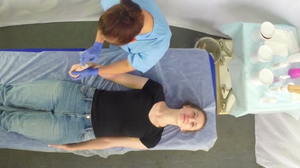 En kosmetolog kvinna gör en shugaring hand borste av klienten. — Stockvideo