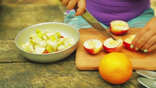 Las manos femeninas se cortan en trozos con un melocotón para ensalada de frutas . — Vídeo de stock