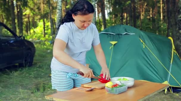 Mujer joven corta un cuchillo de melocotón con un cuchillo para ensalada de frutas en un picnic .. — Vídeos de Stock