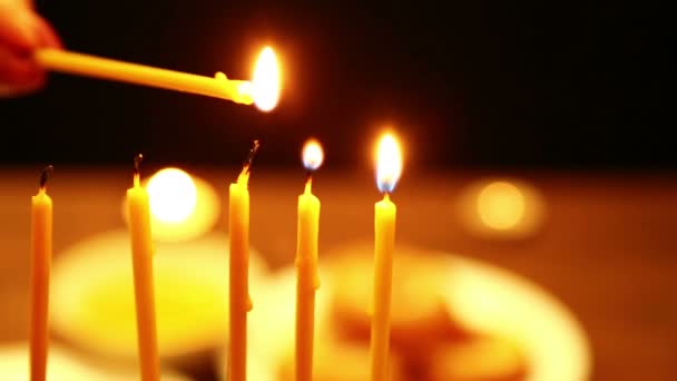 一个女人手里拿着一支蜡烛 在她的帮助下 她点燃了光明节的烛光 一个女人从右向左的第一支蜡烛上点燃蜡烛 相机从右向左移动 — 图库视频影像