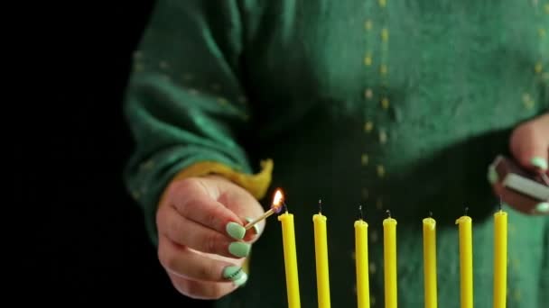 Een vrouw lichten kaarsen met een wedstrijd. — Stockvideo