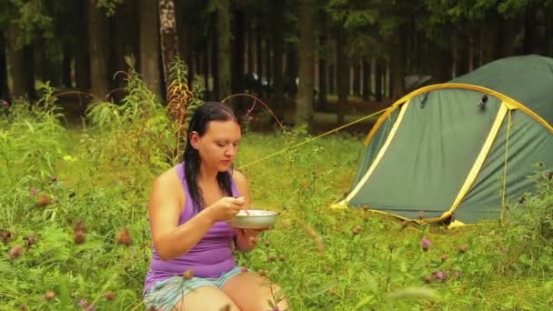 Vrouw zitten in de buurt van tent eten fruitsalade. — Stockvideo