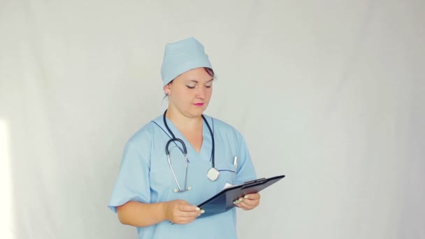 Женщина-врач читает документ и начинает писать рецепт ручкой — стоковое видео
