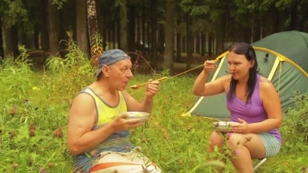 Man en vrouw in de buurt van de tent in het forest eten een fruitsalade. — Stockvideo