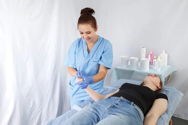 Vrouw arts schoonheidsspecialiste verwijdert de haren op de vingers van de rechterhand vrouw aan de patiënt, de blik is gericht op de hand — Stockfoto