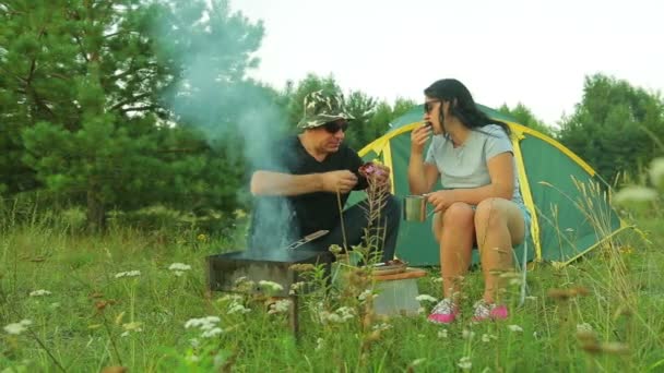 Een man en een vrouw eet shish kebab in de buurt van de tent. — Stockvideo