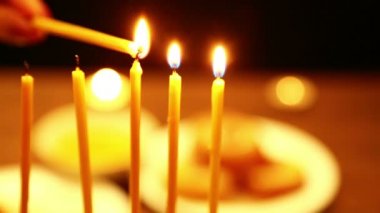 bir kadın bir mum hangi o Hanukkah mum ışıkları yardımı ile onun elinde tutar. İlk mum sağdan sola bir kadın ışık mumlar. yakın çekim. Kamera sağdan sola taşır