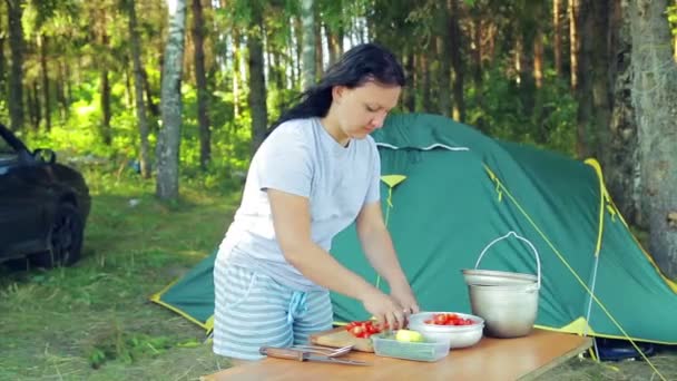 Eine junge Frau legt eine Kirschtomate in eine Salatschüssel für ein Picknick. — Stockvideo