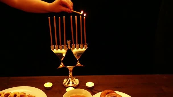 一个女人手里拿着一根燃烧着的蜡烛 在光明节的烛台上点燃蜡烛 一个女人从右向左的第一支蜡烛上点燃蜡烛 烛台站在一个 — 图库视频影像