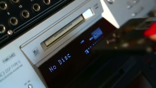 Une main féminine insère un mini disque dans un lecteur argenté 