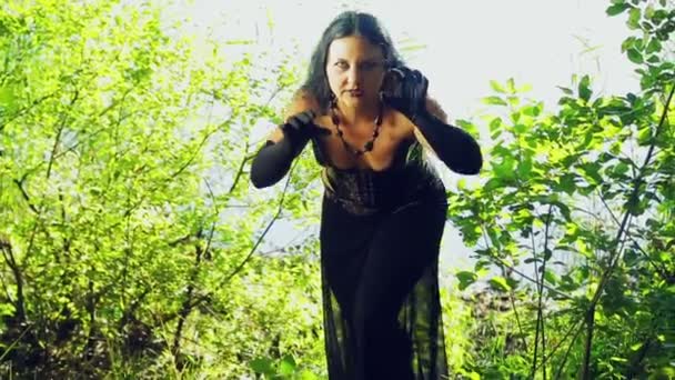 An angry woman witch in black clothes on the shore of the lake. Halloween. Gothick style. — Stock Video