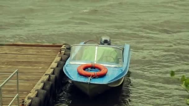 Dalgalar fırtına kayalarda iskelede küçük bir tekne. — Stok video