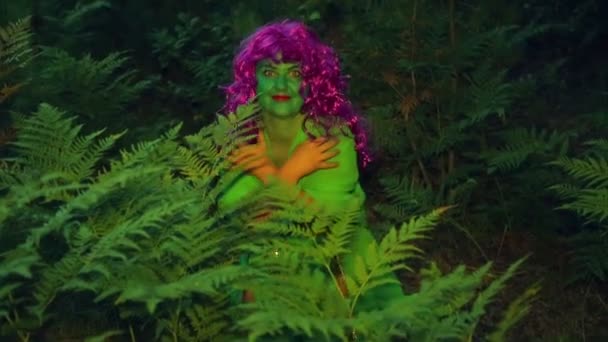Зелёная ведьма вылезает из кустов в сумерках . — стоковое видео