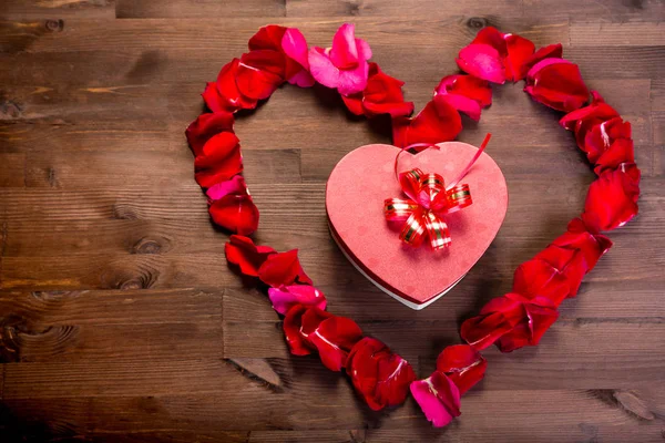 Ahşap masanın üstüne gül lepistas kalp içinde bir hediye bir kalp şeklinde bir kutudur. Kopyalama alanının sol