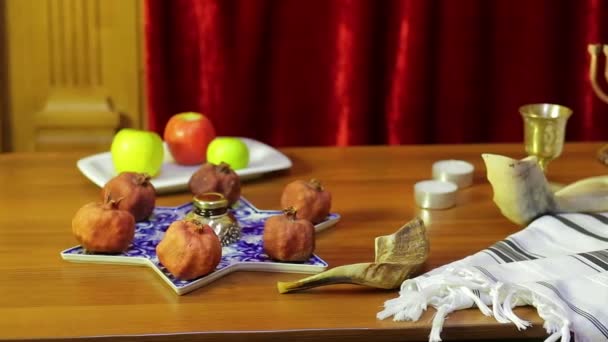 Auf dem Tisch in der Synagoge liegen Symbole der Rosch Haschana: Leckereien und Shofaras neben dem Talit. — Stockvideo