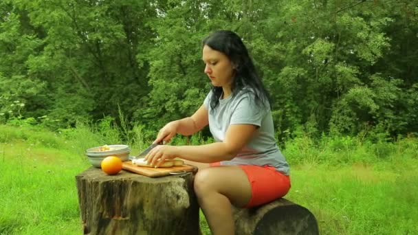 Eine Frau schneidet auf einem Picknick eine Banane für Obstsalat. — Stockvideo