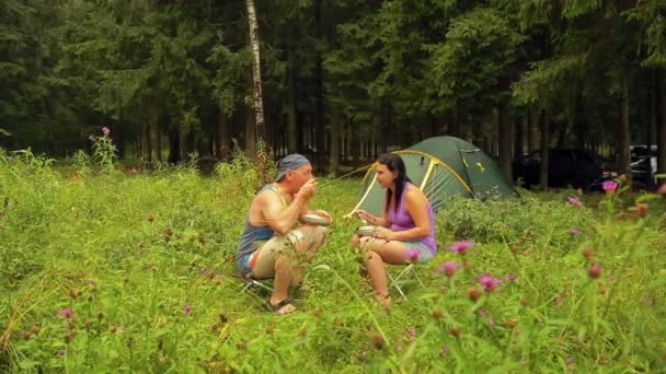 Un uomo con una donna si accovaccia in un campeggio in mezzo a una tenda . — Video Stock