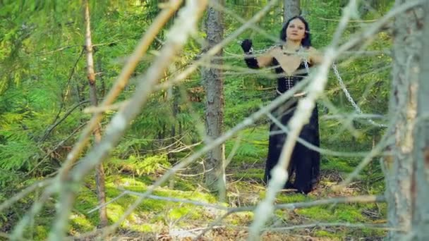 Una joven bruja con ropa negra atada con cadenas, tratando de liberarse. Halloween. Estilo Gothick . — Vídeo de stock
