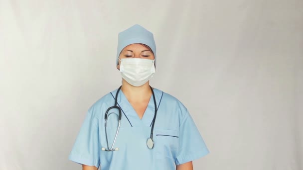 Una doctora con una bata sobre su cara mirando a la cámara. Disparando al plan del medio. La cámara se mueve a la muñeca — Vídeos de Stock