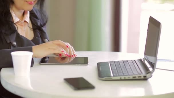 Egy fiatal nő, egy dzseki van működő-ra egy tabletta mellett egy laptop. Közeli kép: — Stock videók