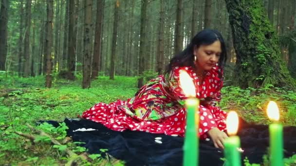 A young gypsy woman lights candles in a circle in the forest. — Stock Video