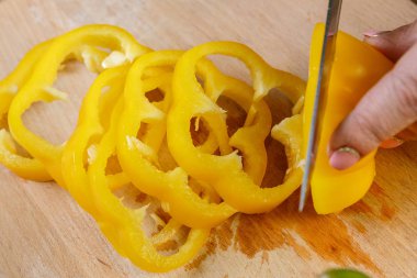 Bir sürü lobules sarı biber bıçakta bir bıçakla bir kesme kurulu eller close-up üzerinde