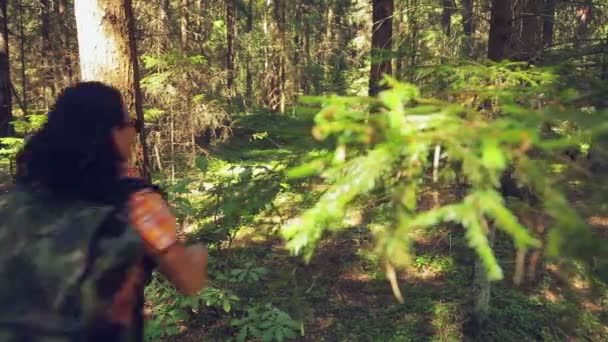 Une femme avec un sac à dos sur le dos court à travers la forêt. Tir par le dos . — Video