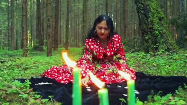 Uma jovem cigana acende velas em um círculo na floresta . — Vídeo de Stock