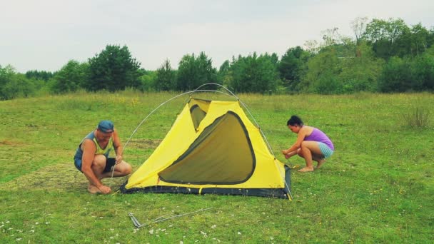 Muž a žena nastavit stan s pomocí oblouků pro upevnění. — Stock video