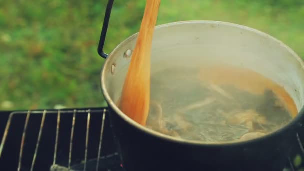 Fuochi bollenti in un fuoco in un bollitore funghi mescolare un cucchiaio di legno . — Video Stock