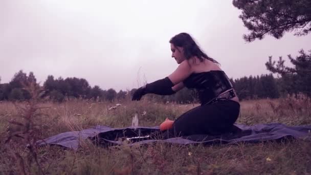 Una joven bruja en negro evoca con piedras blancas en el bosque. Halloween. Estilo Gothick . — Vídeo de stock