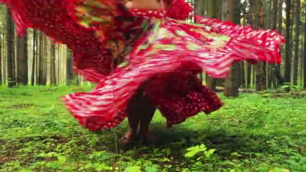 Barefooted woman in a bright gypsy dress whirls in a dance in the forest. — Stock Video