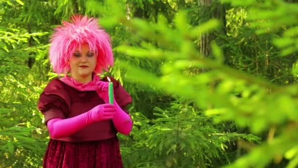 Une jeune sorcière en habits rituels dans une forêt évoque une bougie allumée . — Video