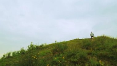 Yağmurlu havalarda dağ gelen bir turist sırtında bir sırt çantası ile iner.