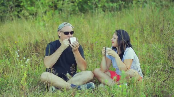 Couple Tourists Sitting Grass Drinking Tea Mugs Talking Overall Plan — Stock Video