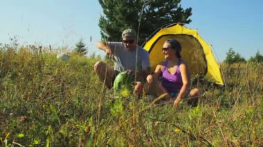 Bir erkek ve bir kadın bir çadır vardır. Bir adam bir karpuz kesme.