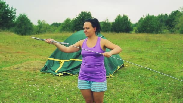 Bir kadın bir çadır yüklemek için metal bir kemer döşeme. — Stok video